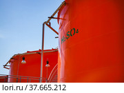 Orange metal storage tanks with sulfuric (sulphuric) acid and its formula on tank. Oil refinery plant warehouse. Close up. Стоковое фото, фотограф Alexey Rezvykh / Фотобанк Лори