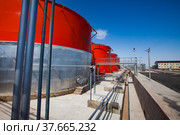 Orange steel storage tanks with acid on sulfuric acid (sulphuric) plant warehouse. Blue sky background. Kzylorda region, Kazakhstan. Стоковое фото, фотограф Alexey Rezvykh / Фотобанк Лори