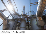 Sulphuric acid plant. Furnace for sulfur burning, tubes for sulphur dioxide. Smoking stack (factory chimney). Blue sky and sun background. Kzylorda region, Kazakhstan. Стоковое фото, фотограф Alexey Rezvykh / Фотобанк Лори