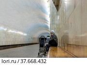 An elderly woman on the bench is waiting for a train at the metro station. (2019 год). Редакционное фото, фотограф Андрей Никитин / Фотобанк Лори