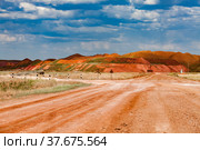 Landscape of bauxite mine (aluminium ore quarry). Orange clay soil and blue sky with clouds. Dump heaps and a road with road signs. Blue sky with cloud. Стоковое фото, фотограф Alexey Rezvykh / Фотобанк Лори