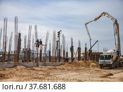 Aktau, Kazakhstan - May 19, 2012: Construction of modern asphaltic bitumen plant. Assembling building columns. Concrete pump filling cement in forms. Worker on column form. Blue sky. Редакционное фото, фотограф Alexey Rezvykh / Фотобанк Лори