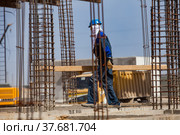 Aktau, Kazakhstan - May 19, 2012 Construction of modern asphaltic bitumen plant. Worker in balaclava mask and reinforcement steel and blue sky on background. Стоковое фото, фотограф Alexey Rezvykh / Фотобанк Лори