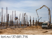 Aktau, Kazakhstan - May 19, 2012: Construction of modern asphaltic bitumen plant. Assembling building columns. Concrete pump filling cement in forms. Worker on column form. Blue sky. Стоковое фото, фотограф Alexey Rezvykh / Фотобанк Лори