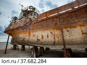 Mangystau, Kazakhstan - May 19, 2012: Old rusted ship on Caspian Sea, Bautino bay, ship-repairing yard. Grey cloudy sky. Стоковое фото, фотограф Alexey Rezvykh / Фотобанк Лори