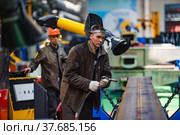 Ekibastuz, Pavlodar region, Kazakhstan - May 28, 2012: Rail car-building plant. Young worker and protective mask. Welding wagon parts with gas-burner. Редакционное фото, фотограф Alexey Rezvykh / Фотобанк Лори