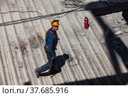 Ekibastuz, Pavlodar region, Kazakhstan - May 28, 2012: GRES-1 steam power station. Industrial climber (builder) and fire extinguisher on metal roof. Стоковое фото, фотограф Alexey Rezvykh / Фотобанк Лори