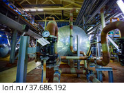 Pavlodar, Kazakhstan - May 29 2012: Caustic chemical plant workshop panorama. Heat exchanger, pressure meter and pipes. Part of chemical reactor. Focus on pressure meter. Short depth of field. Редакционное фото, фотограф Alexey Rezvykh / Фотобанк Лори