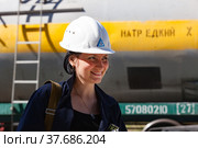 Caustic chemical plant. Young attractive engineer girl in white hardhat posing and smiling on railway tank wagon backgd. (2012 год). Редакционное фото, фотограф Alexey Rezvykh / Фотобанк Лори
