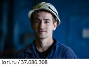 Aksu, Pavlodar region, Kazakhstan - May 29, 2012: Aksu steam power station. Portrait of young caucasian worker in white hardhat with protective glasses. Blurred blue background. Редакционное фото, фотограф Alexey Rezvykh / Фотобанк Лори