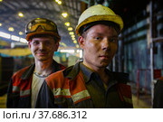 Aksu, Pavlodar region, Kazakhstan - May 29, 2012: Aksu steam power station. Portrait of two young caucasian worker with dirty faces. In yellow hardhats. Background and left worker in out of focus. Редакционное фото, фотограф Alexey Rezvykh / Фотобанк Лори