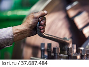 Factory worker's dirty and oily hand and nails in focus. Lathe operator hand only, with tool, close up, no face. Machine's collet clamp on background, motion blurred. Стоковое фото, фотограф Alexey Rezvykh / Фотобанк Лори