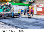 Ремонт дороги возле общественного здания. Дорожные рабочие укладывают асфальт на проезжую часть (2020 год). Редакционное фото, фотограф Александр Бушков / Фотобанк Лори
