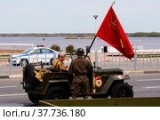 Мужчины в военной форме времен ВОВ, на автомобиле ГАЗ-67, с красным знаменем, на дороге Нижнего Новгорода (2022 год). Редакционное фото, фотограф Nikolay Pestov / Фотобанк Лори