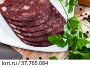 Close up of Spanish smoked blood sausage on white plate on wooden table. Стоковое фото, фотограф Яков Филимонов / Фотобанк Лори