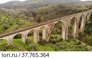 Picturesque aerial view of stone arched viaduct in valley near town of Guadalupe with highway running underneath surrounded by greenery on cloudy spring day, Spain. Стоковое видео, видеограф Яков Филимонов / Фотобанк Лори