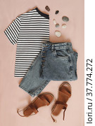 flat lay composition with female top, denim shorts, sandals and a wicker rattan bag on beige background top view. Стоковое фото, фотограф Galina kondratenko / Фотобанк Лори