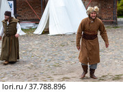 Moscow Russia - september 19 2021: Historical festival Courtyard of the 17th century. Historical reconstruction in the Krutitsky farmstead. A beggar man in historical rags walks through the yard. Редакционное фото, фотограф Yuriy Savin / Фотобанк Лори