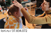 Мастер рисует аквагрим на лице ребенку.The master draws an aquagrim on the child's face. Редакционное видео, видеограф Мария / Фотобанк Лори
