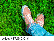 Ноги девушки в розовых кедах на фоне зеленой лужайки. Стильный, модный яркий летний фон. Радуемся лету, теплу, ярким краскам. В парке, непринужденная удобная обувь и стиль одежды, свобода, непосредственность. Фон, обои, открытка. Стоковое фото, фотограф Ludmila Zyubina / Фотобанк Лори