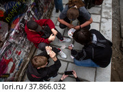 Молодежь играет в карты на улице Арбат в центре города Москвы, Россия (2022 год). Редакционное фото, фотограф Николай Винокуров / Фотобанк Лори
