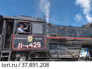 Машинист ретропоезда на паровозной тяге «Рускеальский экспресс» дает паровозный гудок. Платформа железнодорожной станции «Сортавала» (2022 год). Редакционное фото, фотограф Румянцева Наталия / Фотобанк Лори