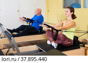 Woman pulling stretch band sitting on pilates training machin. Стоковое фото, фотограф Яков Филимонов / Фотобанк Лори
