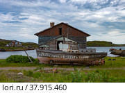 Старая лодка на берегу перед заброшенным домом (2019 год). Редакционное фото, фотограф Алексей Воронцов / Фотобанк Лори