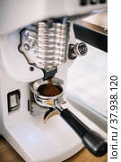Fresh coffee beans grinding from coffee grinding into the portafilter, vertical image. Стоковое фото, фотограф Анастасия Белоусова / Фотобанк Лори