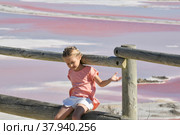 A girl at the Salin-de-Giraud salt farm with pink salty water. Стоковое фото, фотограф Irina Kuchugurina/Gaudy / Фотобанк Лори