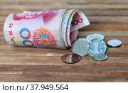 Cash Chinese money. Paper banknotes of 100 yuan denominations and 1 yuan coins on wooden background. Concept of development of  Chinese economy, inflation, investment, business and lending. Стоковое фото, фотограф Виктория Катьянова / Фотобанк Лори