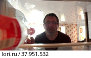 Looking inside refrigerator at an elderly man who takes bottle of soda from shelf. Стоковое видео, видеограф Владимир Григорьев / Фотобанк Лори
