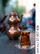 Turkish traditional tea in tulip-shaped glass with cupper colored double teapot. Стоковое фото, фотограф Юлия Паутова / Фотобанк Лори