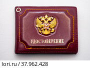 Красная обложка удостоверения с двуглавым орлом - гербом России крупным планом на белом фоне (2022 год). Редакционное фото, фотограф Анна Аникова / Фотобанк Лори