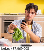 The young man calculating expences for vegetables in kitchen. Стоковое фото, фотограф Elnur / Фотобанк Лори