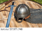 Шлем норманского типа(шлем викингов) и скандинавский меч лежат на деревянном щите. Исторический фестиваль "Былинный Берег - 2022" Стоковое фото, фотограф Виктор Карасев / Фотобанк Лори
