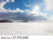 Frequent change of weather characteristic of Baikal Lake, after a blizzard and snowfall, the bright sun shines. View of the Small Sea Strait and Olkhon Island in winter. Стоковое фото, фотограф Виктория Катьянова / Фотобанк Лори