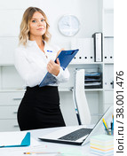 Well-wishing girl with folder of documents is standing in well-lit office. Стоковое фото, фотограф Яков Филимонов / Фотобанк Лори