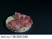 Grain crispbreads crispy rice diet bread and smoked sausage sandwich. Rice cake puffed rice with salami, sausage, balyk, smoked meat on black background. Стоковое фото, фотограф Tae Mi / Фотобанк Лори