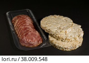 Grain crispbreads crispy rice and diet bread with smoked sausage. Rice cake puffed rice with salami, sausage, balyk, smoked meat on black background. Стоковое фото, фотограф Tae Mi / Фотобанк Лори