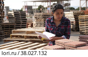 Concentrated hispanic woman worker controlling quantity of tiles at hardware store warehouse. Стоковое видео, видеограф Яков Филимонов / Фотобанк Лори