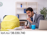 Young male employee looking after new born at workplace. Стоковое фото, фотограф Elnur / Фотобанк Лори