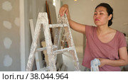 Portrait of tired asian woman standing at stepladder in apartment during repair works. Стоковое видео, видеограф Яков Филимонов / Фотобанк Лори