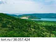 Landscape of Kunashir Island, geothermal lakes among lava domes in the center of Golovnin volcano caldera; the island of Hokkaido is visible in the distance in the sea. Стоковое фото, фотограф Евгений Харитонов / Фотобанк Лори