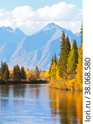 Beautiful autumn landscape with a yellowed trees at the riverside and a mountain range on a sunny afternoon. Siberia, Baikal region, Eastern Sayan Mountains,  Buryatia, Tunka foothill valley, Irkut River. Стоковое фото, фотограф Виктория Катьянова / Фотобанк Лори