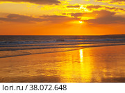 Magnificent southern sunset on the sea. The rays of the setting sun are reflected in the wet sand of a shallow beach. The rich colors of the end of a hot day on the shores of the Atlantic Ocean. Vilamoura, Falesia, Algarve, Portugal. Стоковое фото, фотограф Виктория Катьянова / Фотобанк Лори