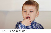 The boy eats candy and tries to get stuck pieces. Стоковое видео, видеограф Потийко Сергей / Фотобанк Лори