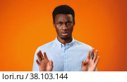 Young african man rejecting something, saying no against orange background. Стоковое видео, видеограф Сергей Толмачёв / Фотобанк Лори