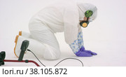 Man in white chemical protection suit holds metal detector. Стоковое видео, видеограф Aleksey Kidisyuk / Фотобанк Лори