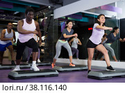 African american man in group of people working out with steppers in fitness center. Стоковое фото, фотограф Яков Филимонов / Фотобанк Лори